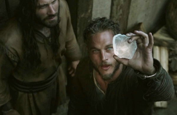 Ragnar Lothbrok holding a translucent sunstone toward the sky in the television series Vikings